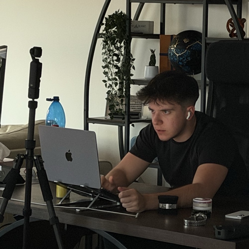 Mario De Luca am Schreibtisch vor seinem Laptop, daneben ein Kamera-Stativ